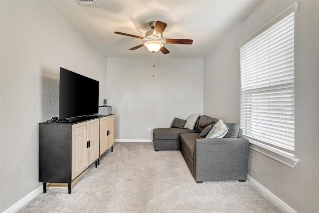 living room featuring light colored carpet, a ceiling fan, and baseboards