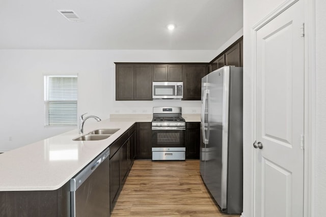 182 Geode Gln, Maxwell, TX 78656 - kitchen with stainless steel appliances, a sink, dark brown cabinetry, a peninsula, and light wood-type flooring