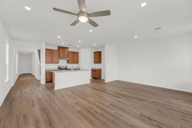 201 Lucky Texan Rd, Jarrell, TX 76537 - kitchen with under cabinet range hood, brown cabinets, open floor plan, recessed lighting, and wood finished floors
