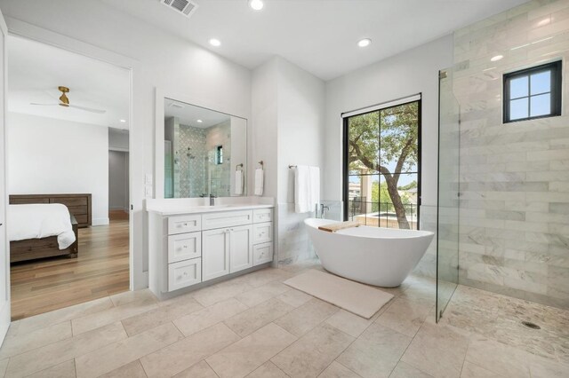 ensuite bathroom with a freestanding tub, vanity, tiled shower, and a wealth of natural light
