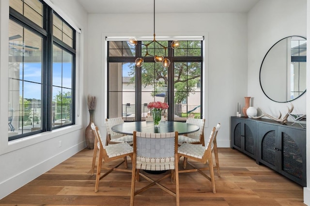dining space with baseboards, a chandelier, and light wood-type flooring