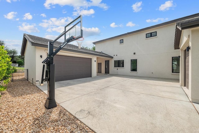 exterior space featuring stucco siding, fence, driveway, and a garage