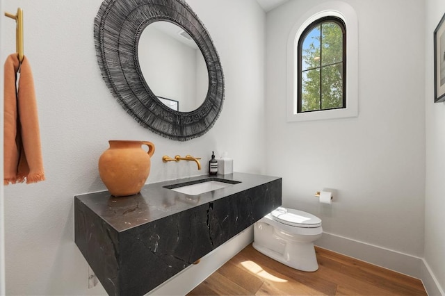 bathroom with baseboards, a sink, wood finished floors, and toilet