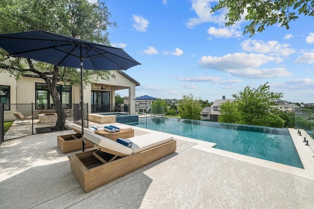 view of swimming pool with a patio, a pool with connected hot tub, and a fire pit