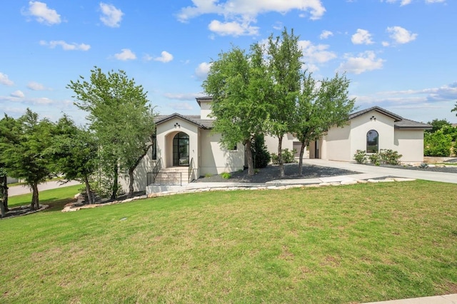 view of front facade with stucco siding, driveway, and a front lawn
