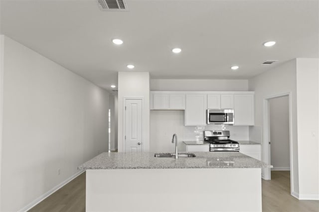 kitchen with a sink, appliances with stainless steel finishes, white cabinetry, and visible vents