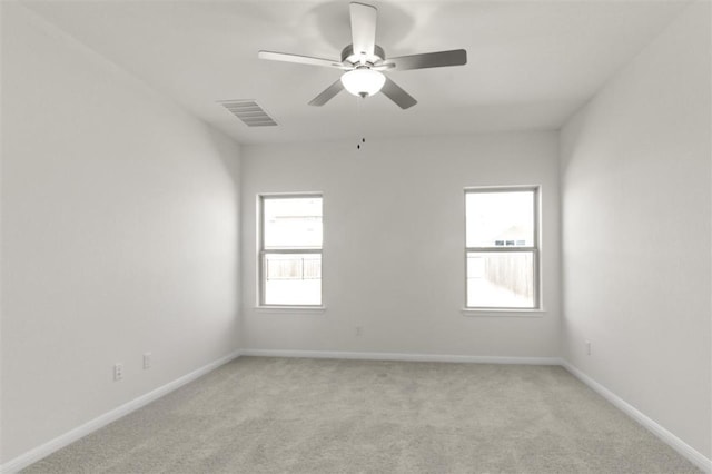 unfurnished room with light colored carpet, a ceiling fan, visible vents, and baseboards