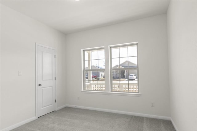 empty room featuring baseboards and light colored carpet