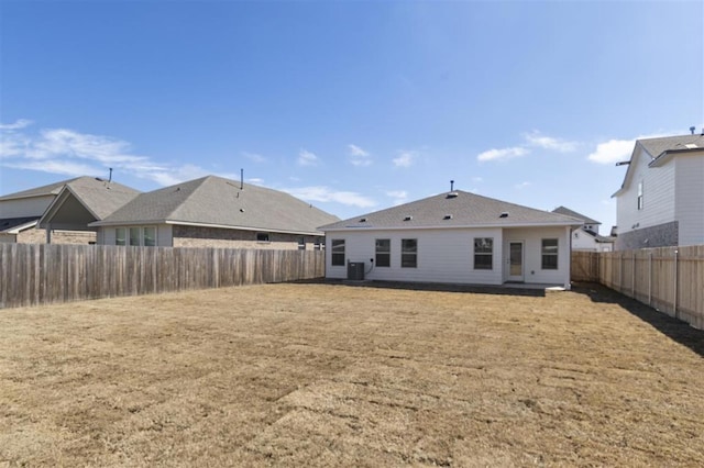 rear view of house with a lawn, a fenced backyard, and central air condition unit