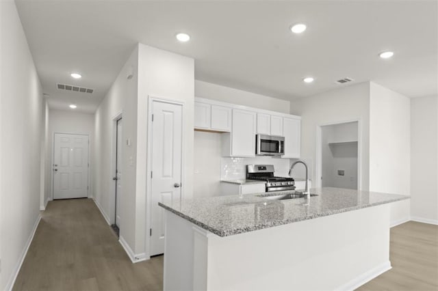kitchen featuring appliances with stainless steel finishes, a sink, light wood-style flooring, white cabinetry, and visible vents