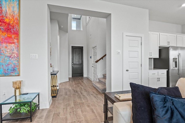 476 Wild Pecan Loop, Buda, TX 78610 - interior space featuring light wood-style flooring, baseboards, stairway, and a towering ceiling