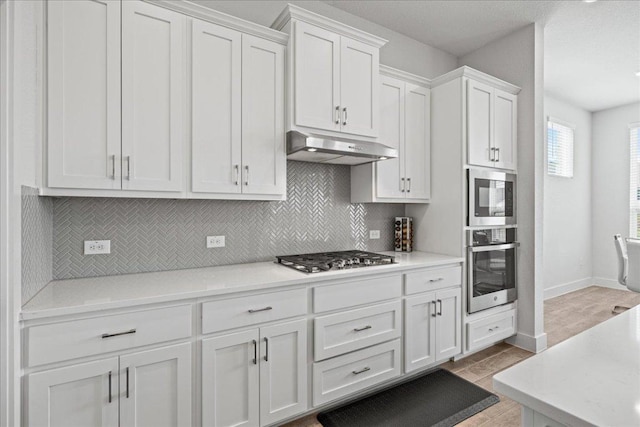 476 Wild Pecan Loop, Buda, TX 78610 - kitchen with stainless steel appliances, under cabinet range hood, white cabinetry, and light countertops
