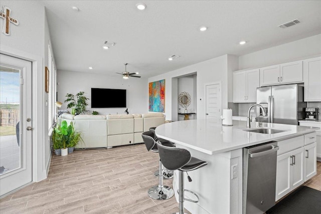 476 Wild Pecan Loop, Buda, TX 78610 - kitchen featuring appliances with stainless steel finishes, a sink, white cabinetry, light wood-style floors, and light countertops