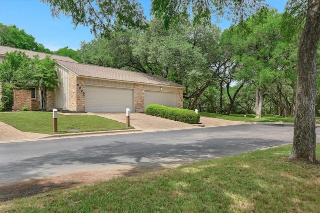 view of front of home with a garage, a front yard, driveway, and brick siding