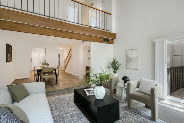 living room featuring stairway, visible vents, wood finished floors, and a towering ceiling