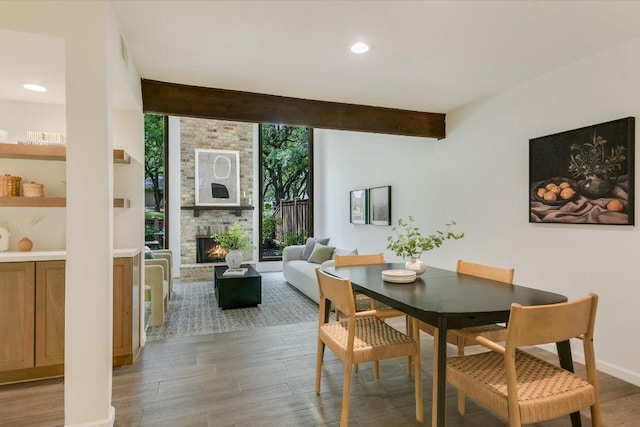 dining area featuring recessed lighting, beam ceiling, wood finished floors, and a fireplace