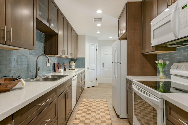 kitchen with white appliances, light countertops, a sink, and light floors