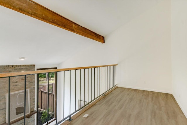 corridor featuring baseboards, lofted ceiling with beams, and wood finished floors
