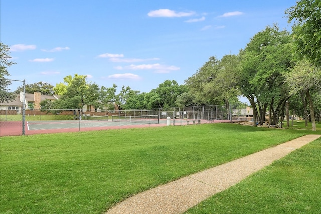 view of property's community with fence, a tennis court, and a yard