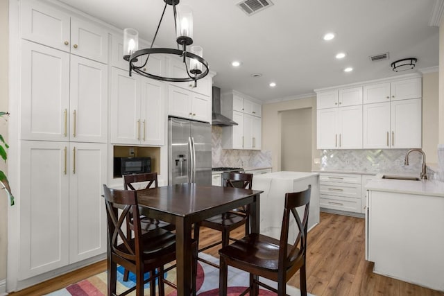 9417 Hopeland Dr, Austin, TX 78749 - kitchen featuring a sink, stainless steel refrigerator with ice dispenser, wall chimney exhaust hood, black microwave, and a chandelier