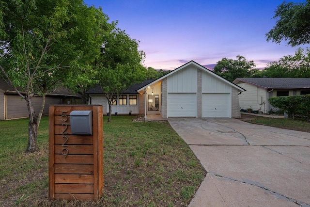 view of front of house featuring a lawn, concrete driveway, a garage, and brick siding