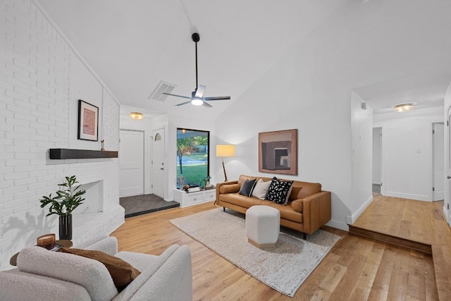living room featuring visible vents, light wood finished floors, a brick fireplace, a ceiling fan, and vaulted ceiling