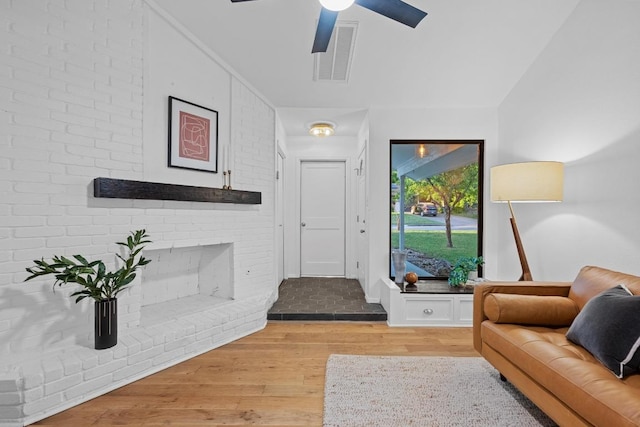 living room featuring visible vents, light wood finished floors, ceiling fan, and a fireplace