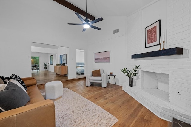 living area with visible vents, a fireplace, light wood-style floors, ceiling fan, and high vaulted ceiling