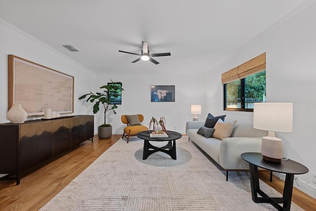 living room featuring ornamental molding, a ceiling fan, light wood finished floors, and visible vents
