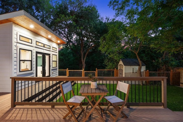 deck featuring an outdoor structure, a lawn, fence, and a shed