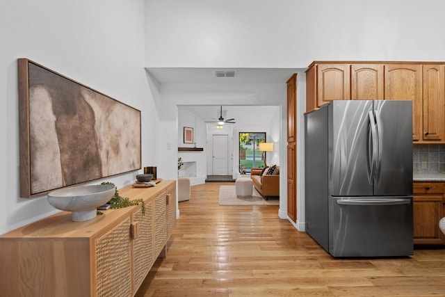 kitchen with visible vents, freestanding refrigerator, light wood-type flooring, tasteful backsplash, and a ceiling fan