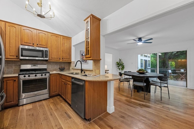 kitchen featuring a sink, brown cabinetry, stainless steel appliances, decorative backsplash, and glass insert cabinets
