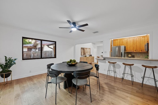 dining room featuring a ceiling fan, visible vents, baseboards, light wood-style floors, and ornamental molding