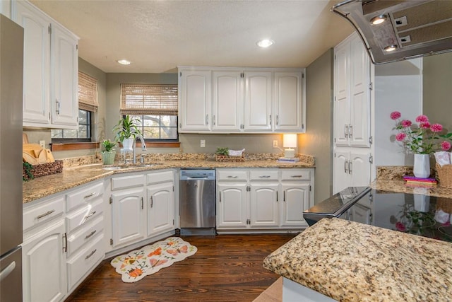 kitchen with white cabinets, dark wood-style flooring, a sink, wall chimney exhaust hood, and stainless steel appliances