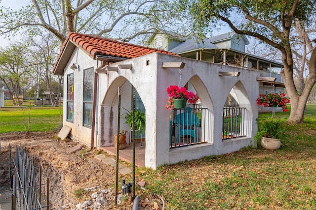 view of side of property with a tile roof and stucco siding