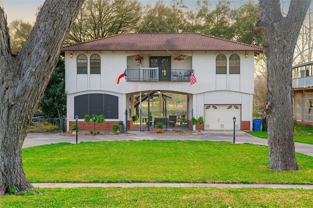 view of front of home with stucco siding, a front yard, a tile roof, and a balcony
