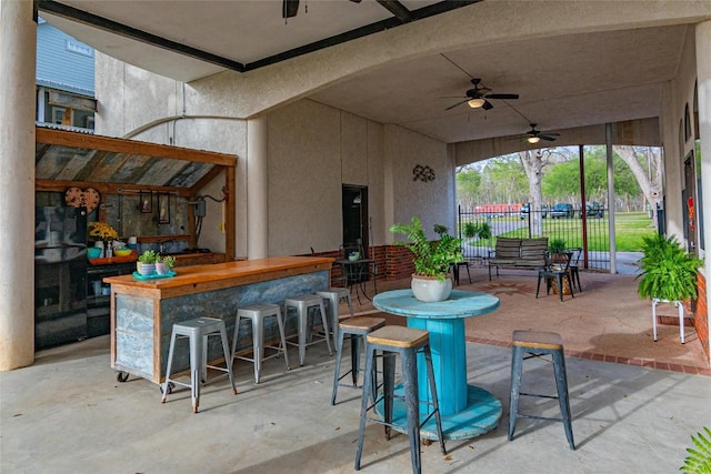 view of patio with ceiling fan, fence, and outdoor dry bar