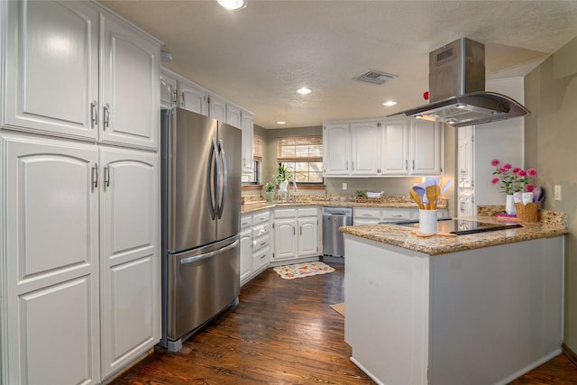 kitchen with white cabinets, stainless steel appliances, a peninsula, island range hood, and visible vents