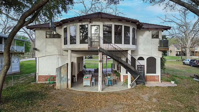 rear view of house featuring a sunroom, stucco siding, stairway, and a patio