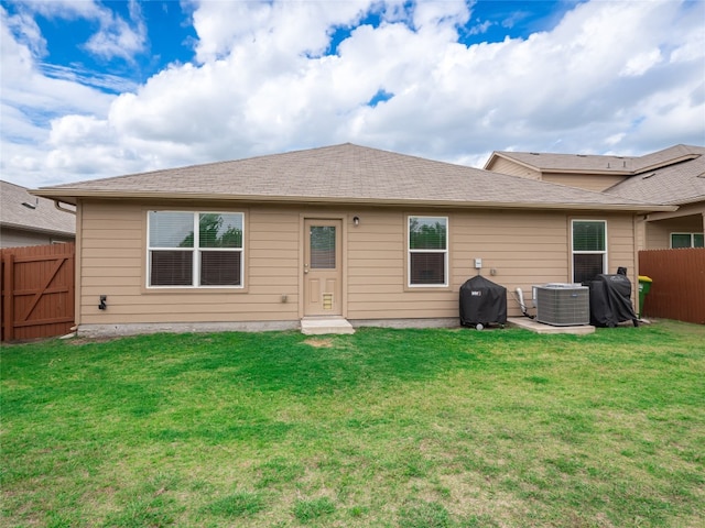 rear view of house featuring central air condition unit, a lawn, and a fenced backyard