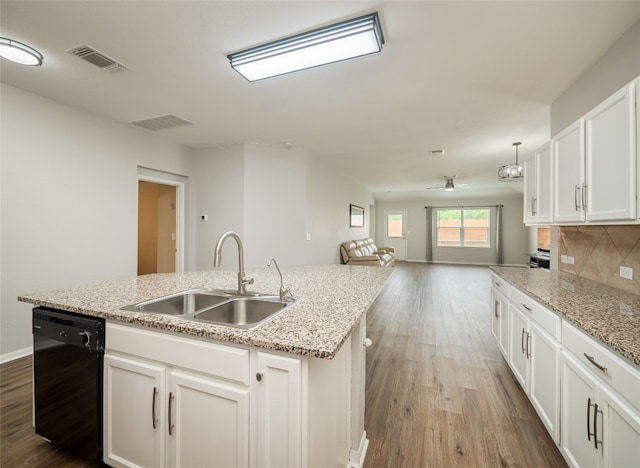 kitchen with visible vents, open floor plan, black dishwasher, a center island with sink, and a sink