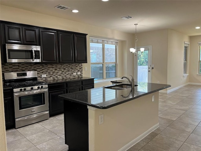 5817 Scenic Lake Dr, Georgetown, TX 78626 - kitchen with stainless steel appliances, a sink, dark cabinets, light tile patterned floors, and decorative backsplash