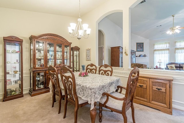 dining space featuring visible vents, lofted ceiling, light colored carpet, arched walkways, and ceiling fan with notable chandelier