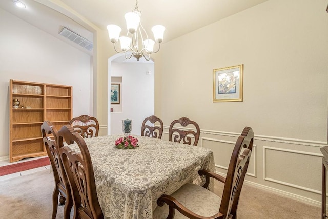dining room featuring carpet floors, visible vents, wainscoting, an inviting chandelier, and arched walkways