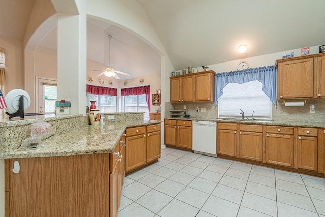 kitchen with white dishwasher, arched walkways, decorative backsplash, and a sink