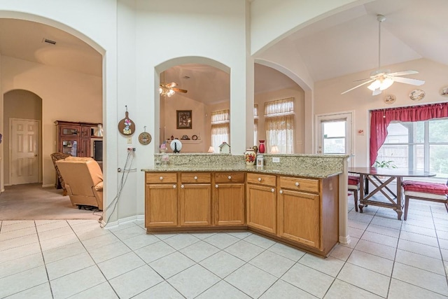 kitchen with a ceiling fan, light stone countertops, and light tile patterned flooring