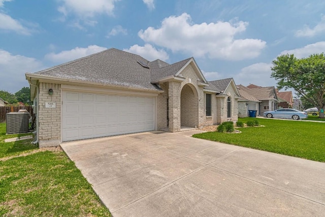 single story home with a front lawn, central AC unit, a shingled roof, an attached garage, and driveway