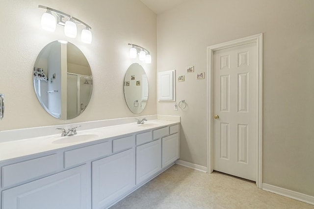 bathroom featuring a sink, baseboards, an enclosed shower, and double vanity