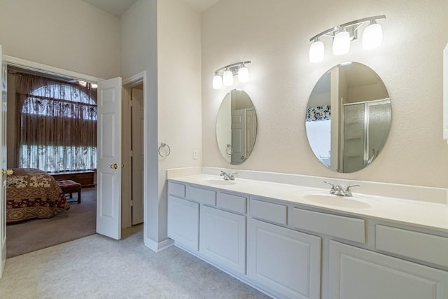 bathroom featuring an enclosed shower, double vanity, and a sink