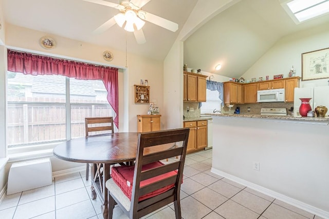 dining space featuring light tile patterned floors, baseboards, a ceiling fan, and vaulted ceiling